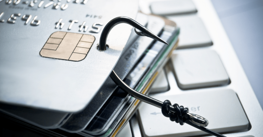credit card phishing - piles of credit cards with a fish hook on computer keyboard